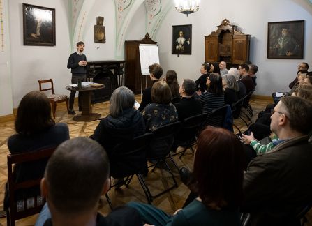 Fotografia mężczyzny z brodą przemawiającego do widowni