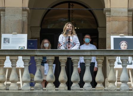 Fotografia. Kobieta w ozdobnym ukraińskim stroju ludowym przemawia ze szczytu schodów przed Willą Decjusza.