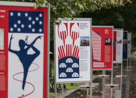A photograph. An opening of the outdoor exhibition titled Polish Americans, American poles at planty in Krakow. posters standing in a row.