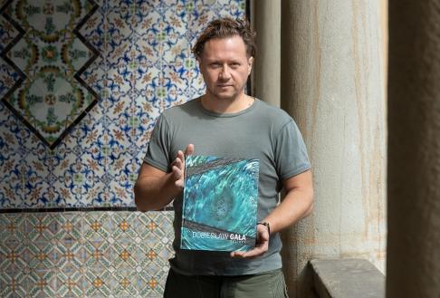 Fotografia mężczyzny trzymającego książkę na tle orientalnych kafli ceramicznych