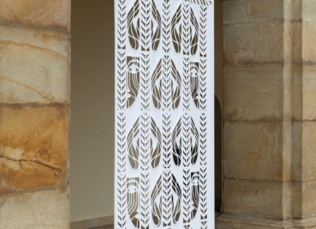 a photograph. large-format cutout with a traditional pattern, displayed between the columns of arcades on the facade of the Decius villa.