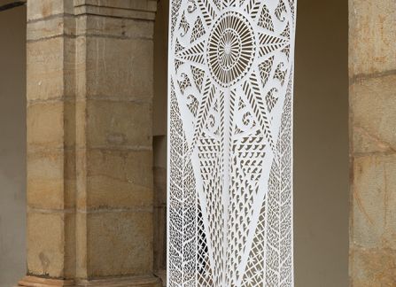 a photograph. large-format cutout with a traditional pattern, displayed between the columns of arcades on the facade of the Decius villa.